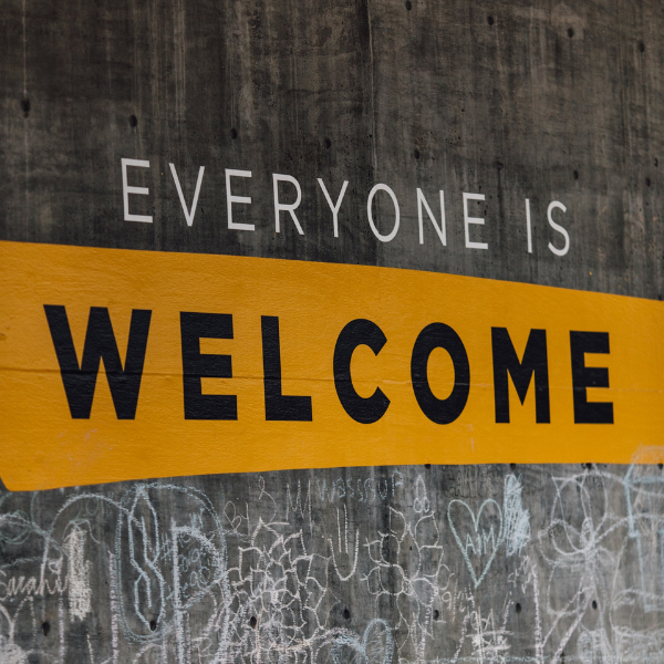 Image of a concrete wall with text painted on it that reads "Everyone is Welcome"