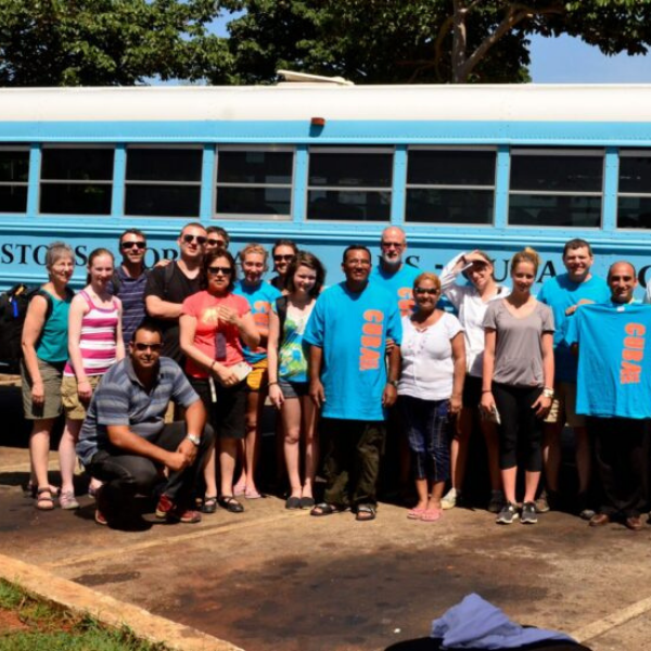 Image of several people standing together in front of a bus.